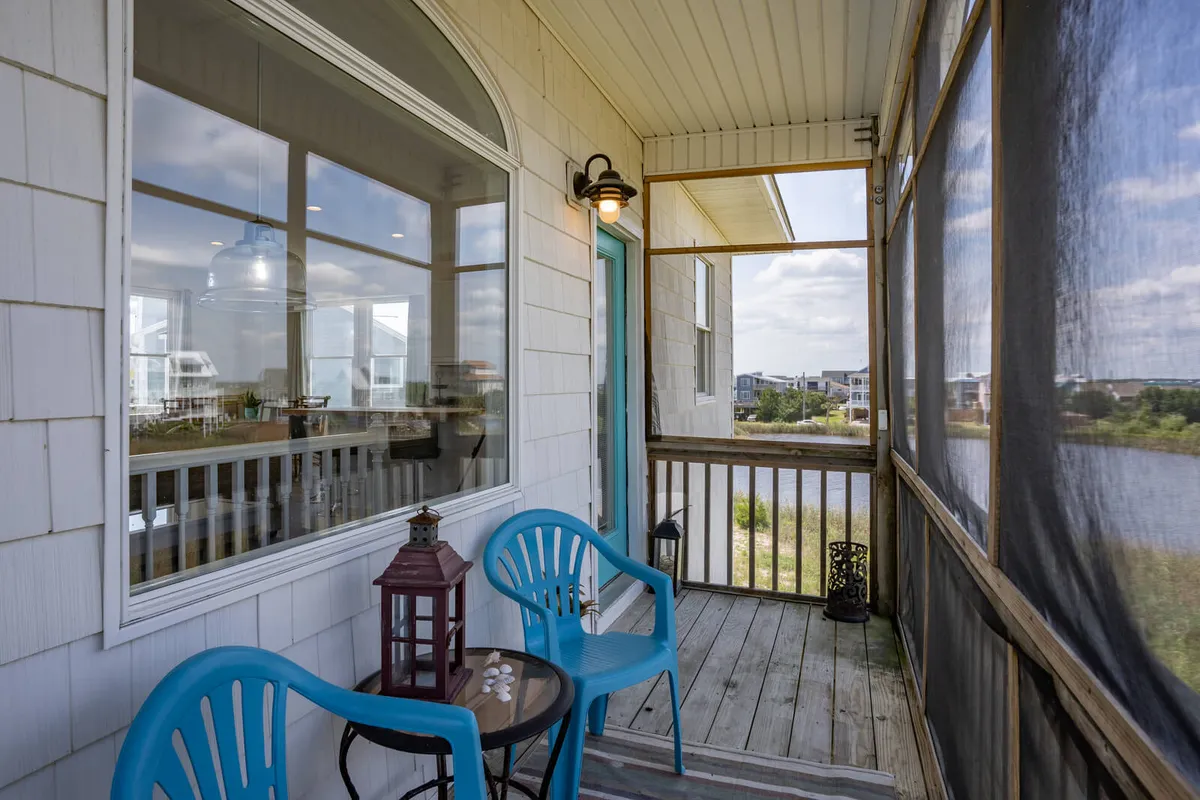 An inviting exterior patio setup featuring blue chairs and a small table, all oriented toward a tranquil water view. The soft lighting and cozy arrangement hint at moments spent enjoying coffee at sunrise, evening chats, or unwinding after exploring the town.