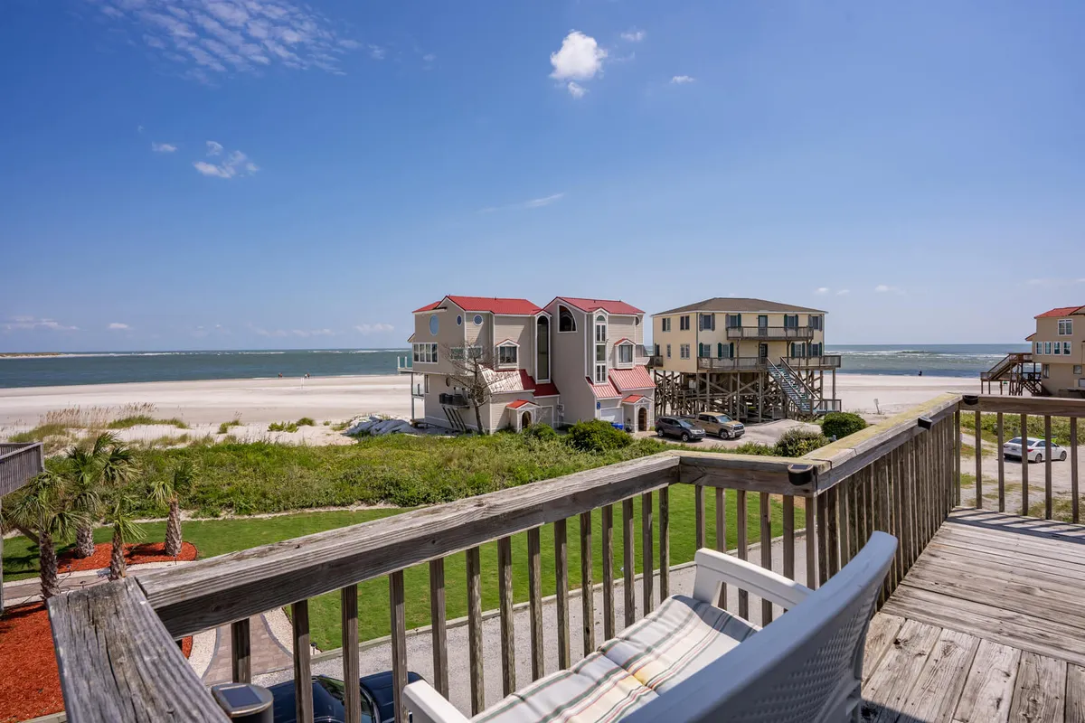 A vibrant beachfront view showcasing colorful houses set against a wide, open sky, with the sandy beach stretching out and inviting visitors to sunbathe, beachcomb, or gather with friends. The image exudes a lively and inviting coastal atmosphere, ideal for highlighting the neighborhood's appeal.